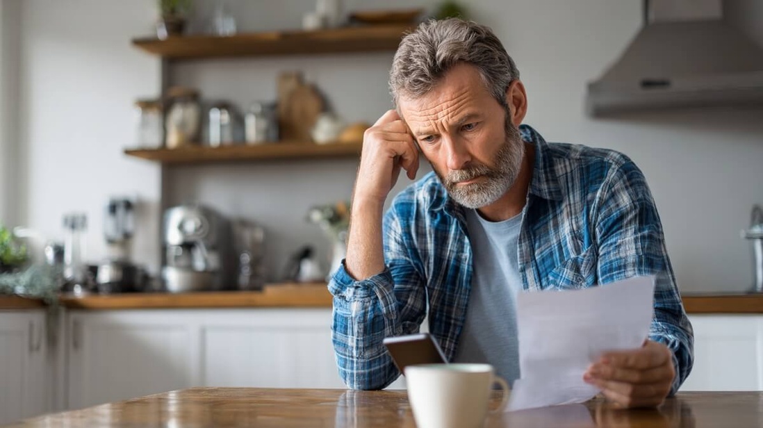 Un retraité consulte son relevé de pension sur smartphone avec une expression préoccupée © SeniorActu