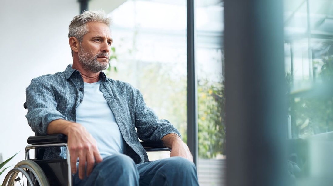 Homme senior handicapé en fauteuil roulant attendant seul l'arrivée de son aide à domicile © SeniorActu