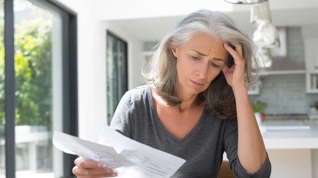 Une jeune retraitée examine ses factures de mutuelle santé avec inquiétude © SeniorActu Une jeune retraitée examine ses factures de mutuelle santé avec inquiétude © SeniorActu