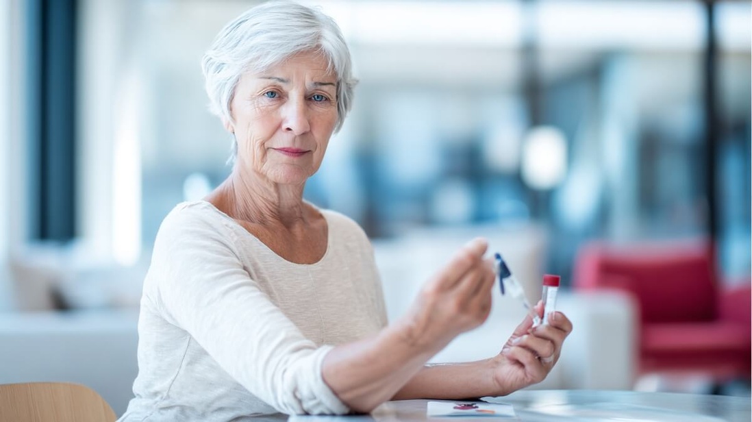 Une femme senior effectue un test sanguin par piqûre au doigt à domicile © SeniorActu