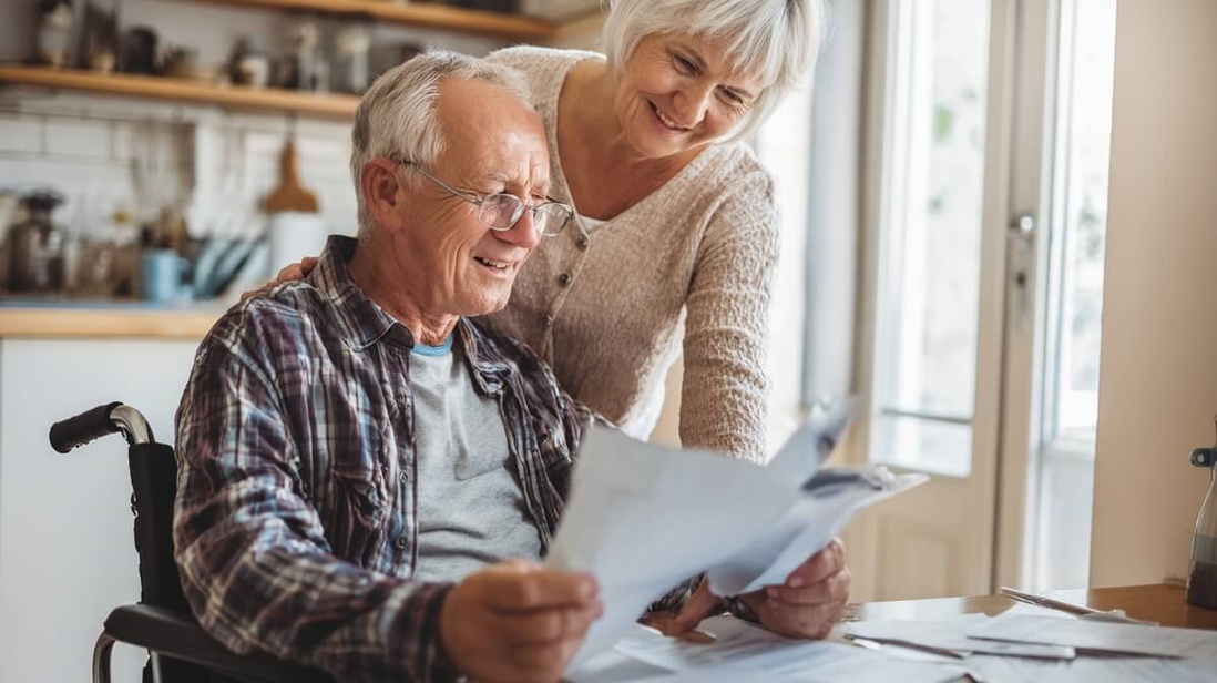 Retraité handicapé en fauteuil roulant consultant des documents MDPH avec sa compagne © SeniorActu