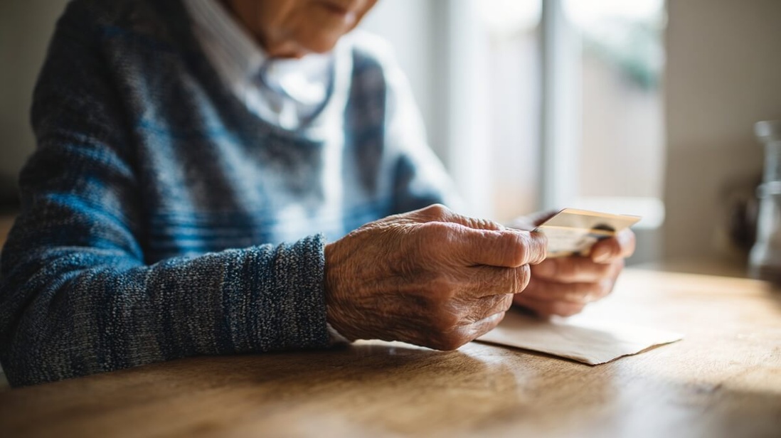 Senior examinant une carte bancaire suspecte reçue par courrier © SeniorActu