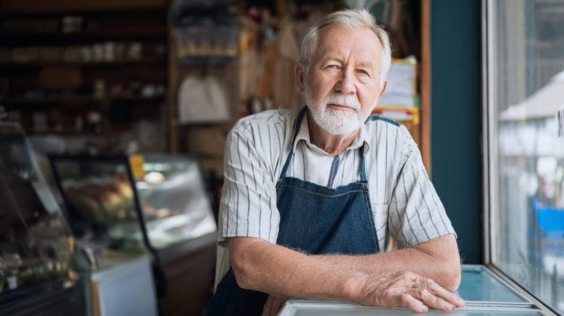 Retraité travaillant derrière un comptoir de petit commerce pour compléter sa petite pension © SeniorActu Retraité travaillant derrière un comptoir de petit commerce pour compléter sa petite pension © SeniorActu