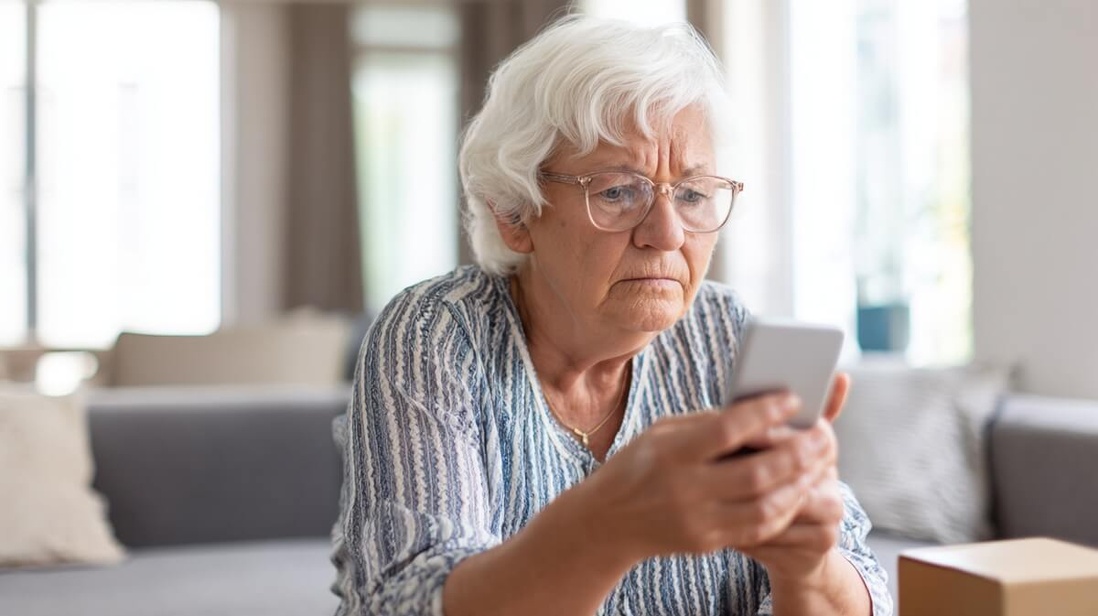 Retraitée regardant un SMS suspect sur son téléphone à côté d'un colis, illustrant les arnaques Leboncoin © SeniorActu Retraitée regardant un SMS suspect sur son téléphone à côté d'un colis, illustrant les arnaques Leboncoin © SeniorActu