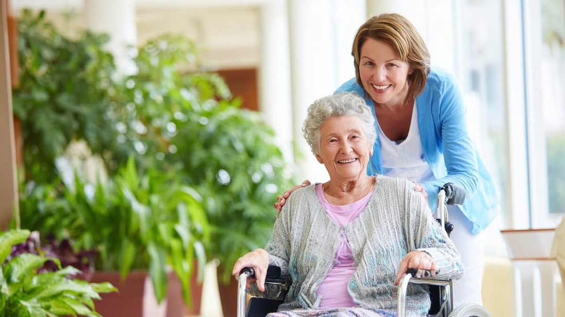 Une fille avec sa mère en fauteuil roulant dans le hall d'un EHPAD © SeniorActu