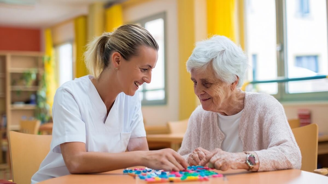 Aide-soignante accompagnant une résidente âgée lors d'un atelier mémoire en EHPAD © SeniorActu