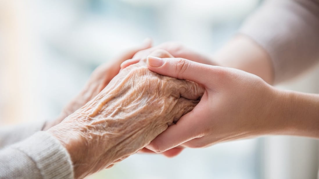 Main rassurante d'une aidante tenant celle d'une personne âgée en EHPAD © SeniorActu Main rassurante d'une aidante tenant celle d'une personne âgée en EHPAD © SeniorActu