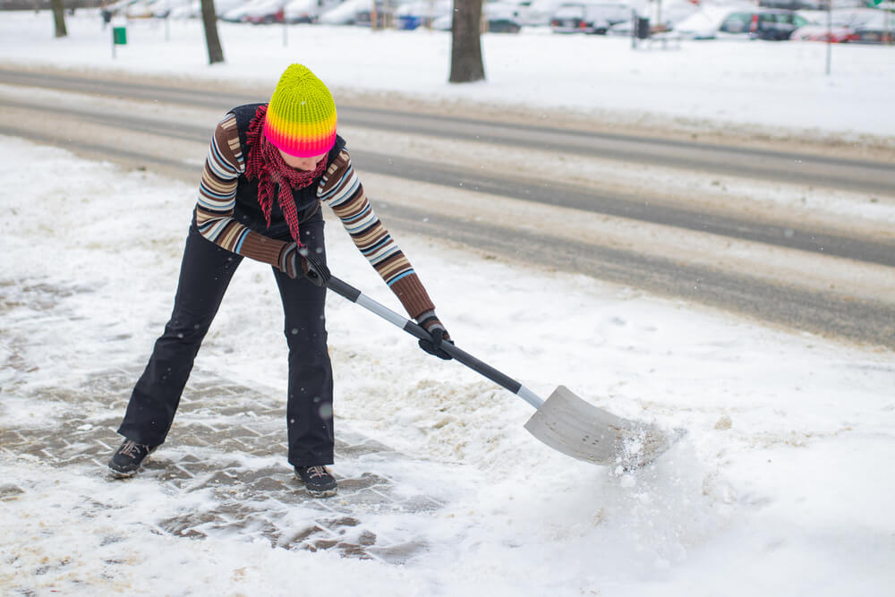 Femme qui déneige devant son domicile ©Shutterstock Femme qui déneige devant son domicile ©Shutterstock