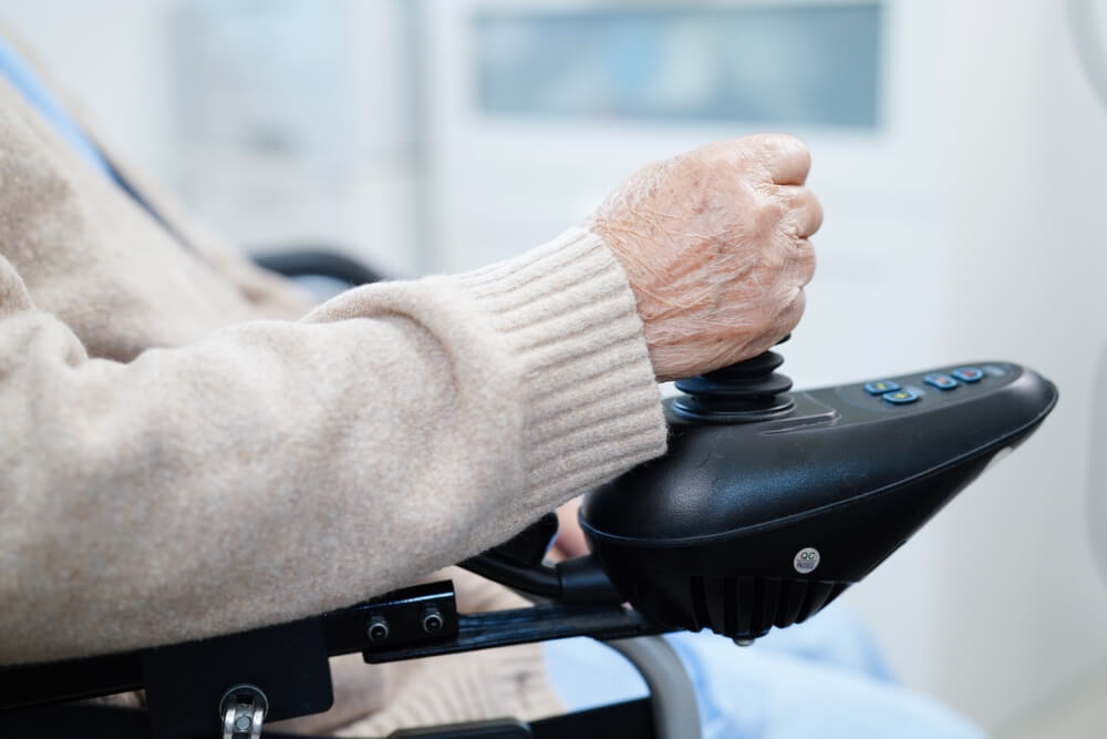 Personne âgée en fauteuil roulant électrique ©Shuttestock