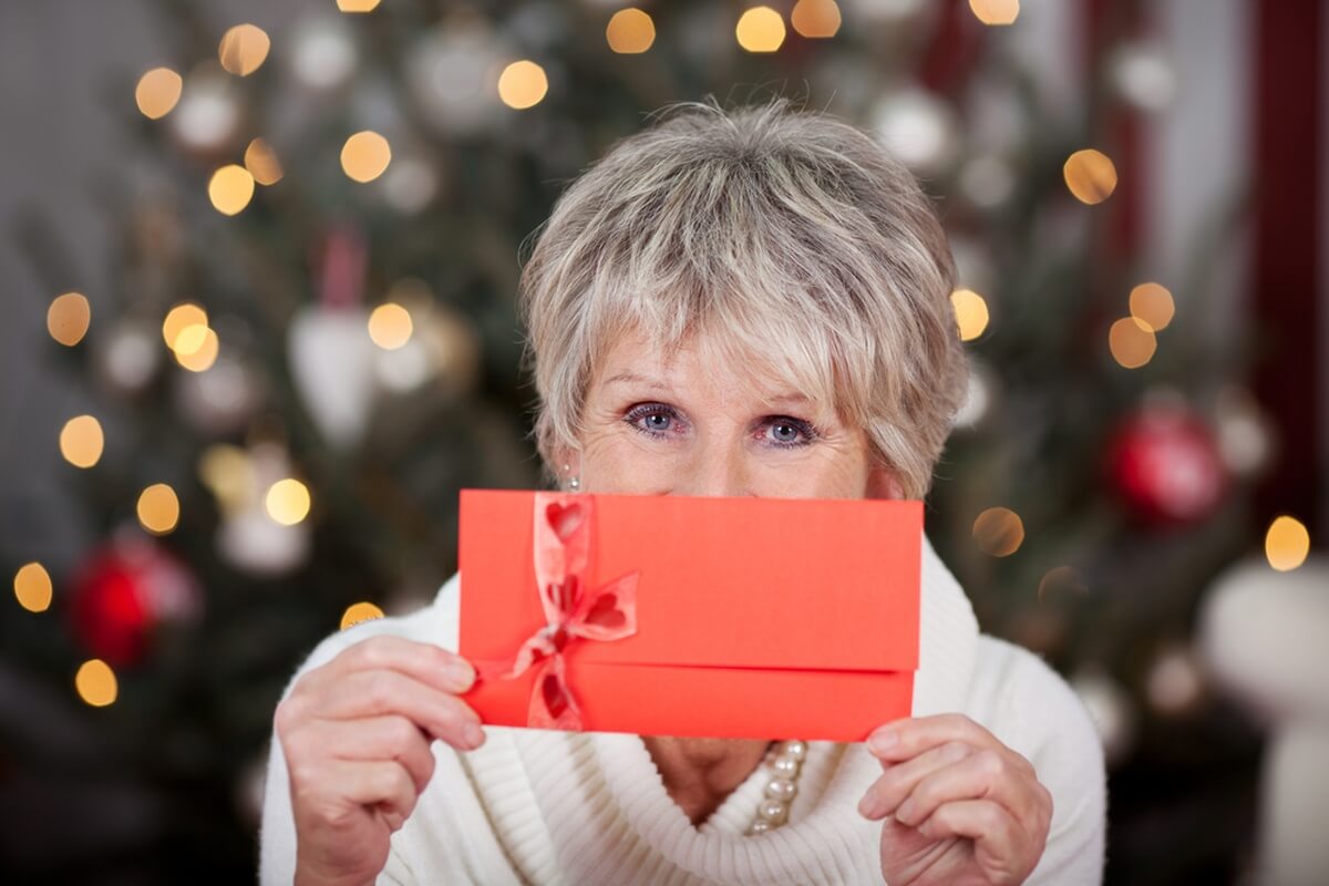 Senior offrant une enveloppe d'argent à Noël présent d'usage fiscalité © stockfour/Shutterstock