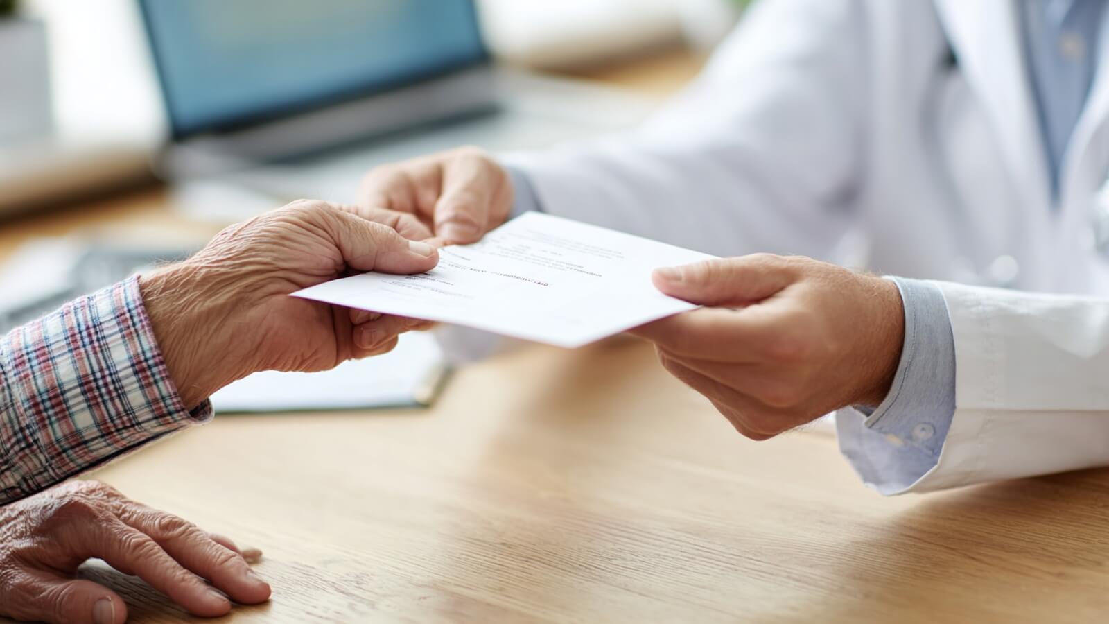 Médecin urologue tendant une ordonnance à un patient senior lors d'une consultation pour des troubles de l'éjaculation après 70 ans